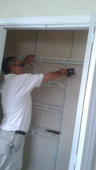 Mario installing white wire shelving inside a reach-in closet with a drill