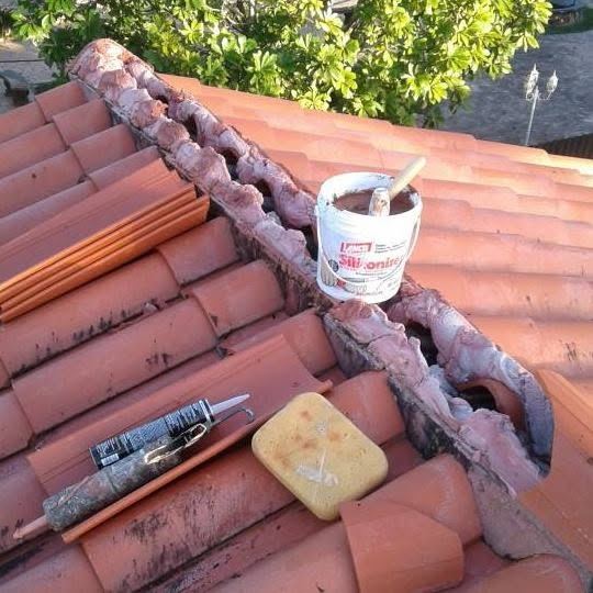 Barrel tile roof ridge being repaired with fresh mortar, caulk gun and sponge on the tiles